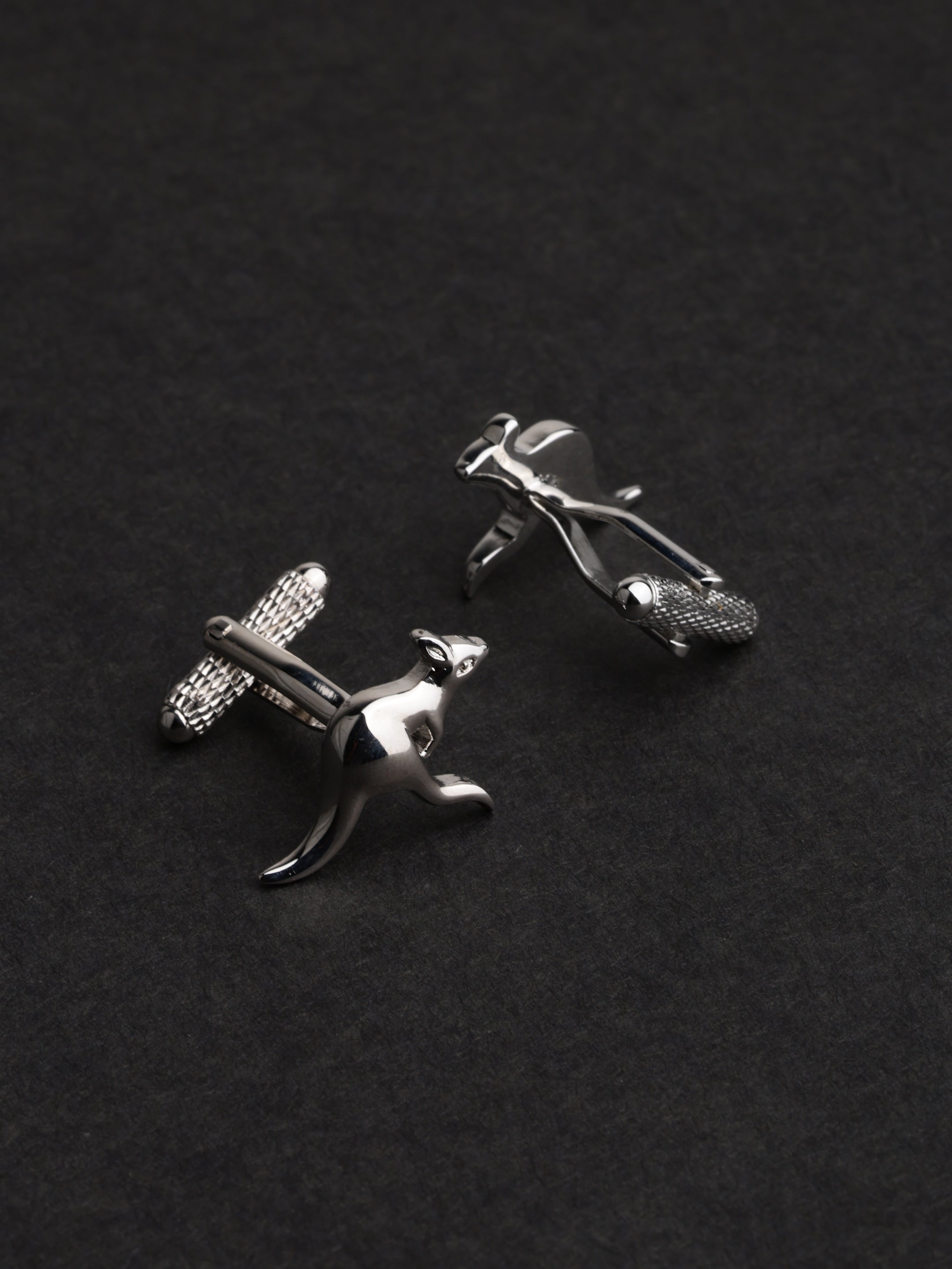 Silver cufflinks shaped like a person on a black background