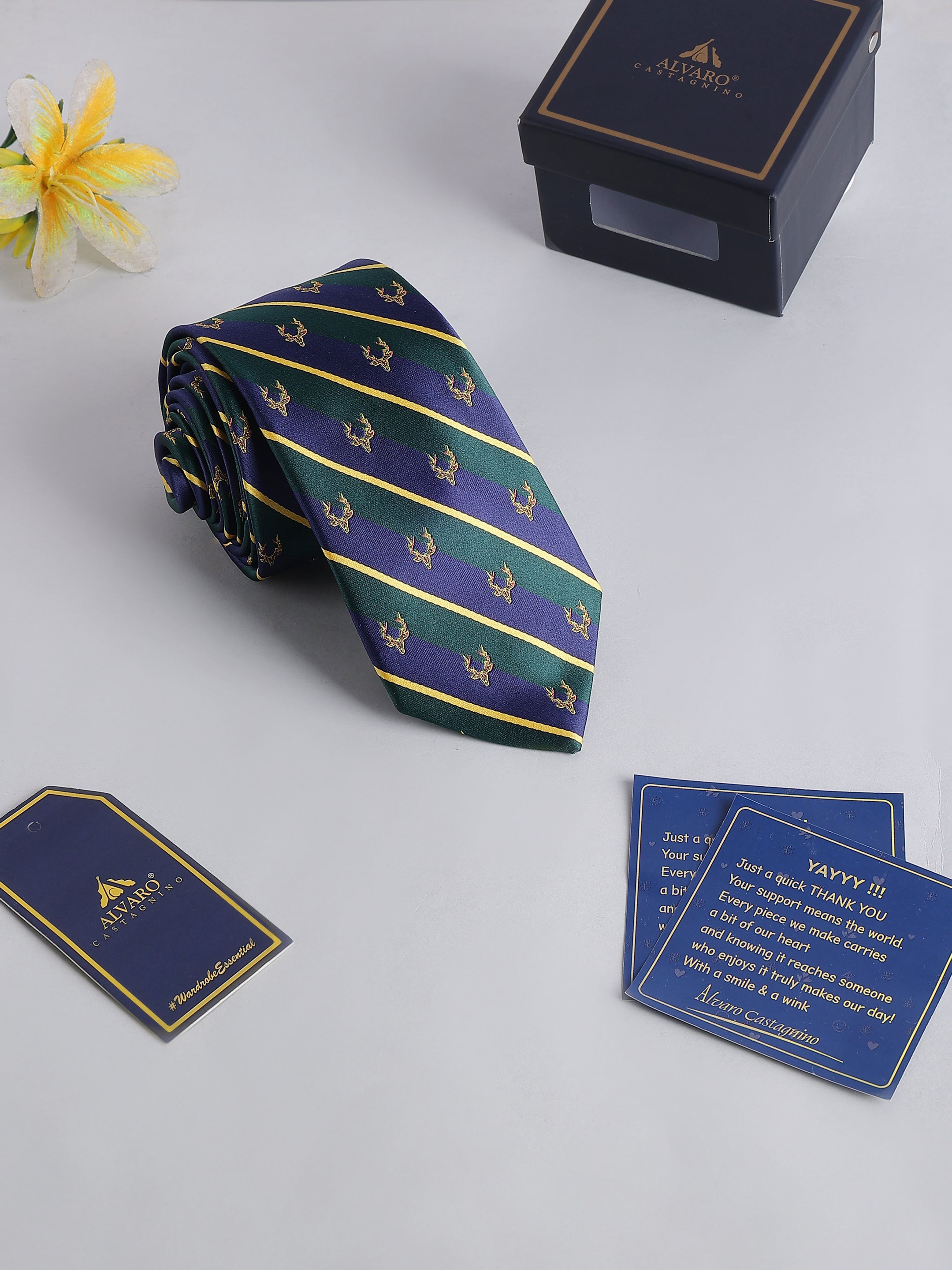 Navy and green striped tie with decorative box and cards on a light gray background