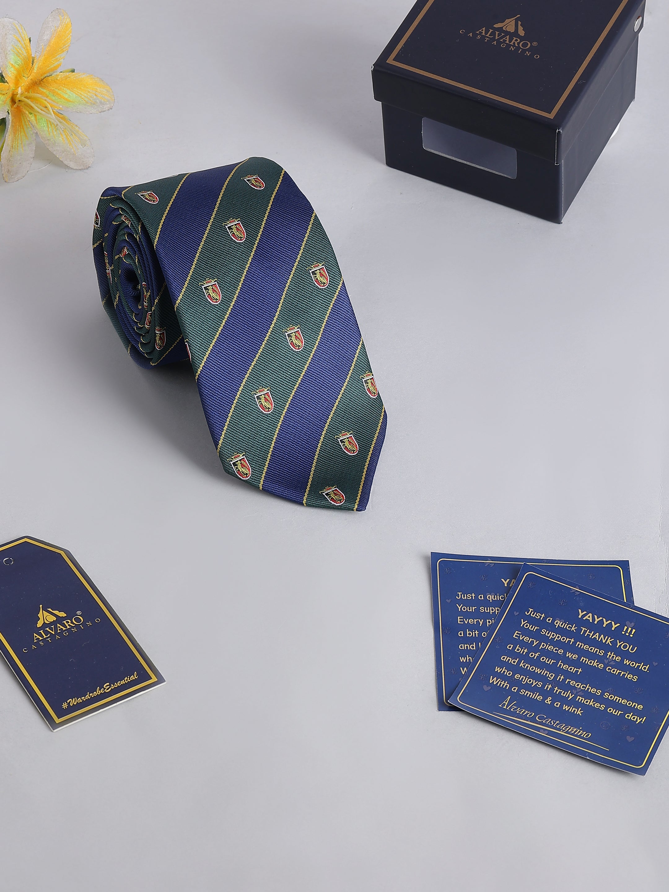 Blue and green striped tie with a box and cards on a light gray background
