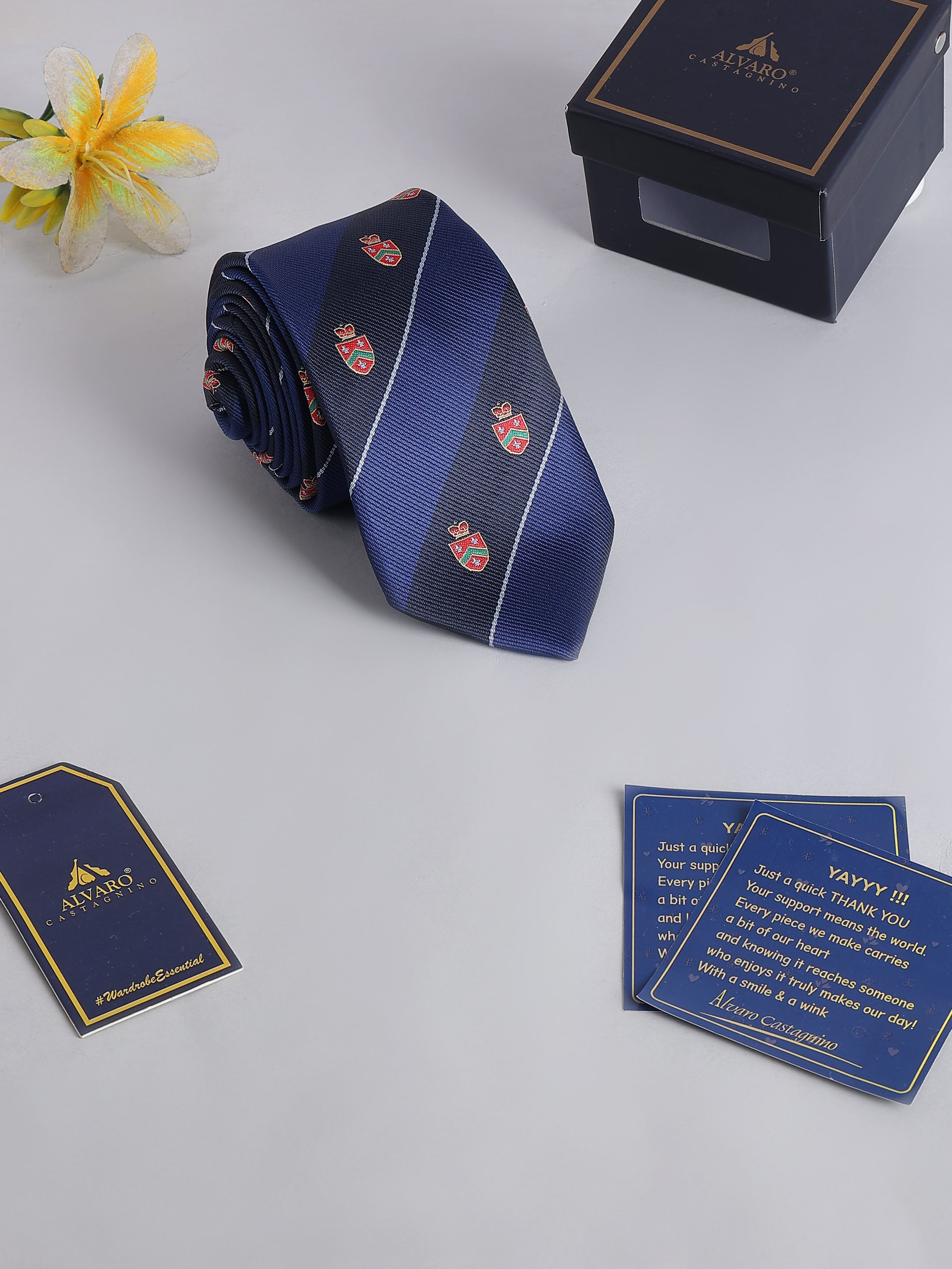 Blue tie with red floral patterns on a white surface with 'Alvaro' branding.
