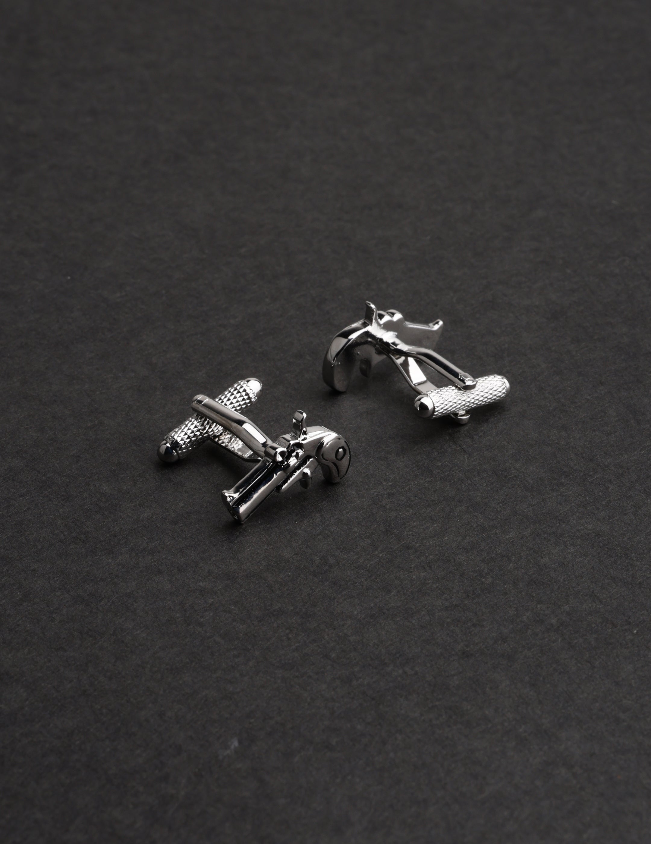 Silver airplane-shaped cufflinks on a dark gray background