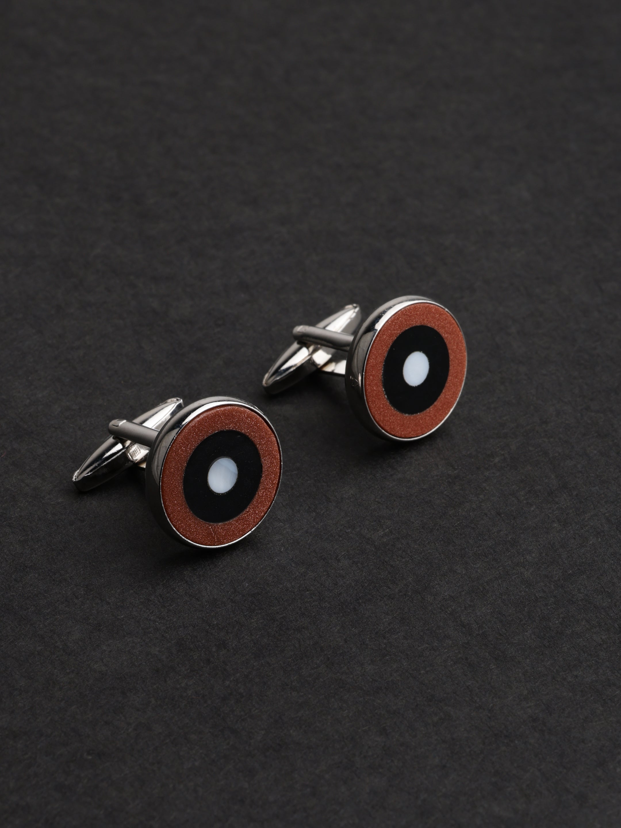 Pair of round cufflinks with a black and red design on a dark background
