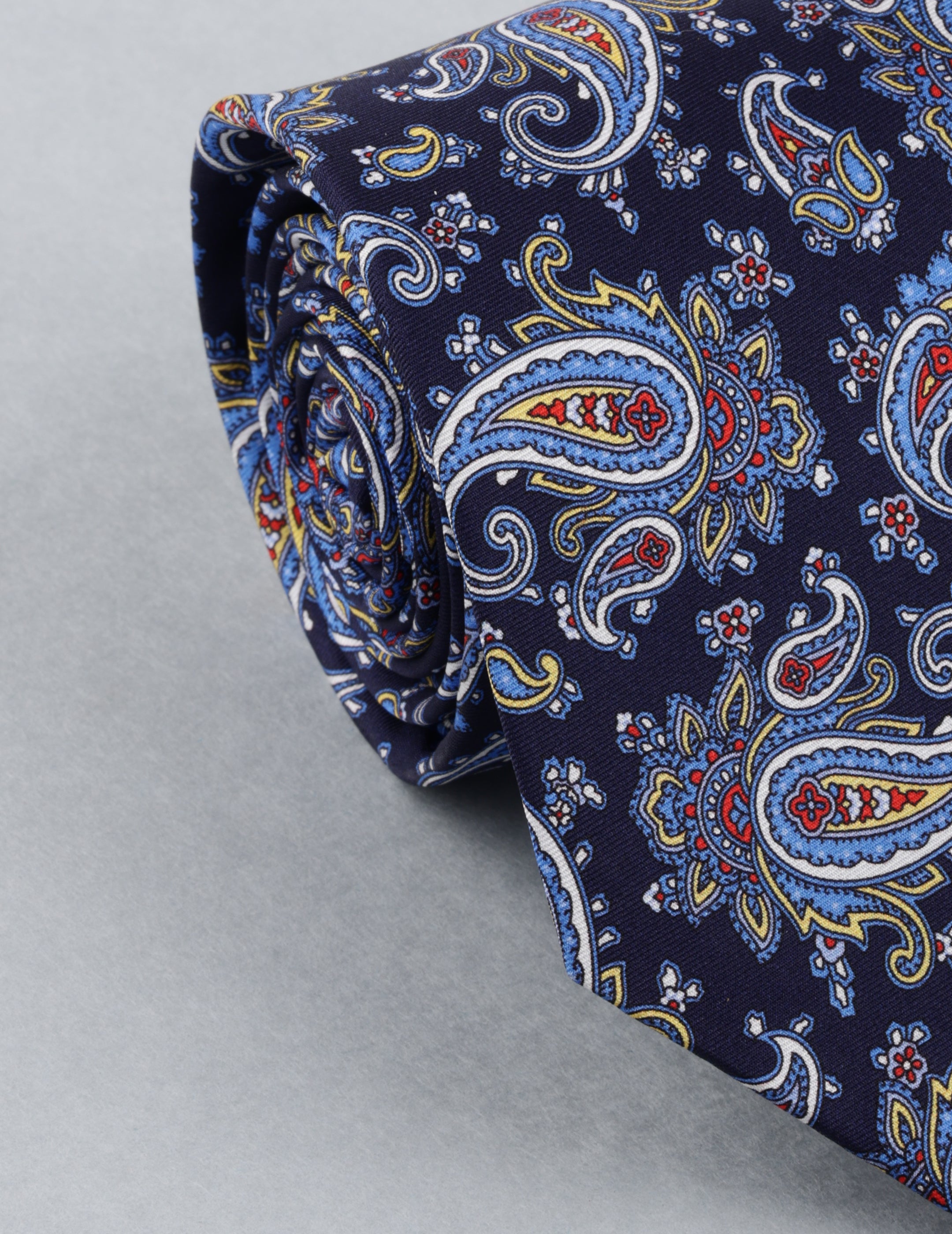 Navy blue paisley patterned tie on a light gray background