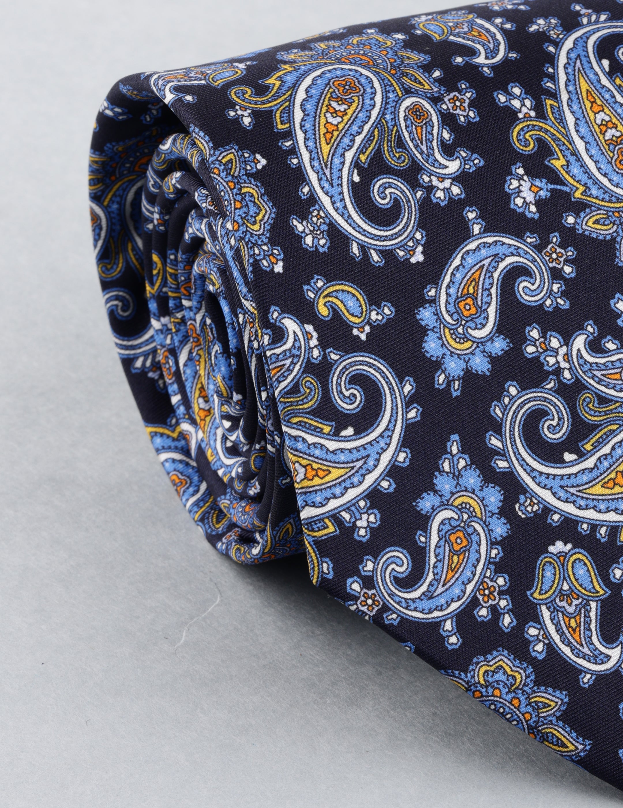 Navy blue paisley patterned tie on a light gray background