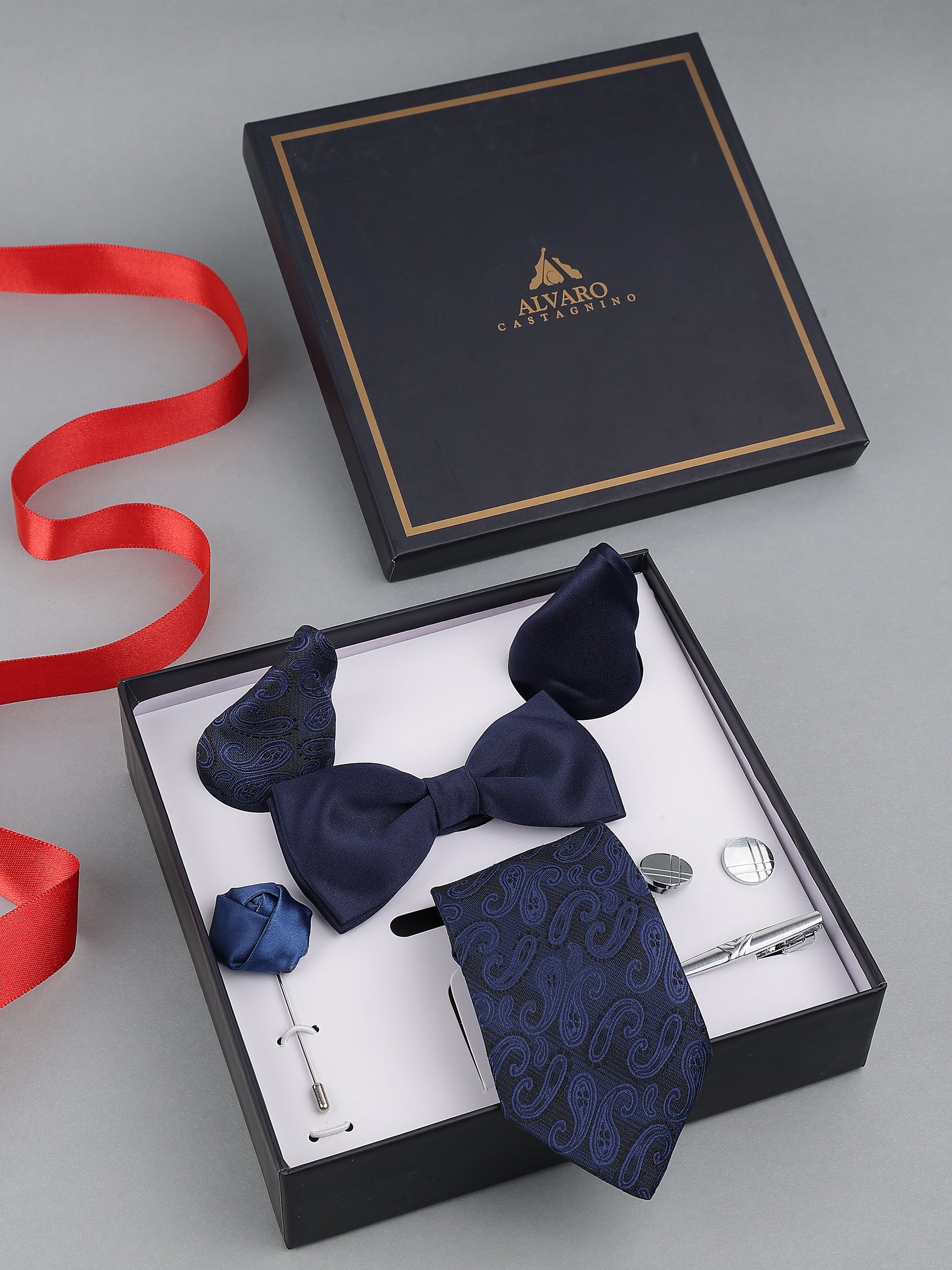 Navy blue bow tie, pocket square, and cufflinks set in a branded box with a red ribbon.